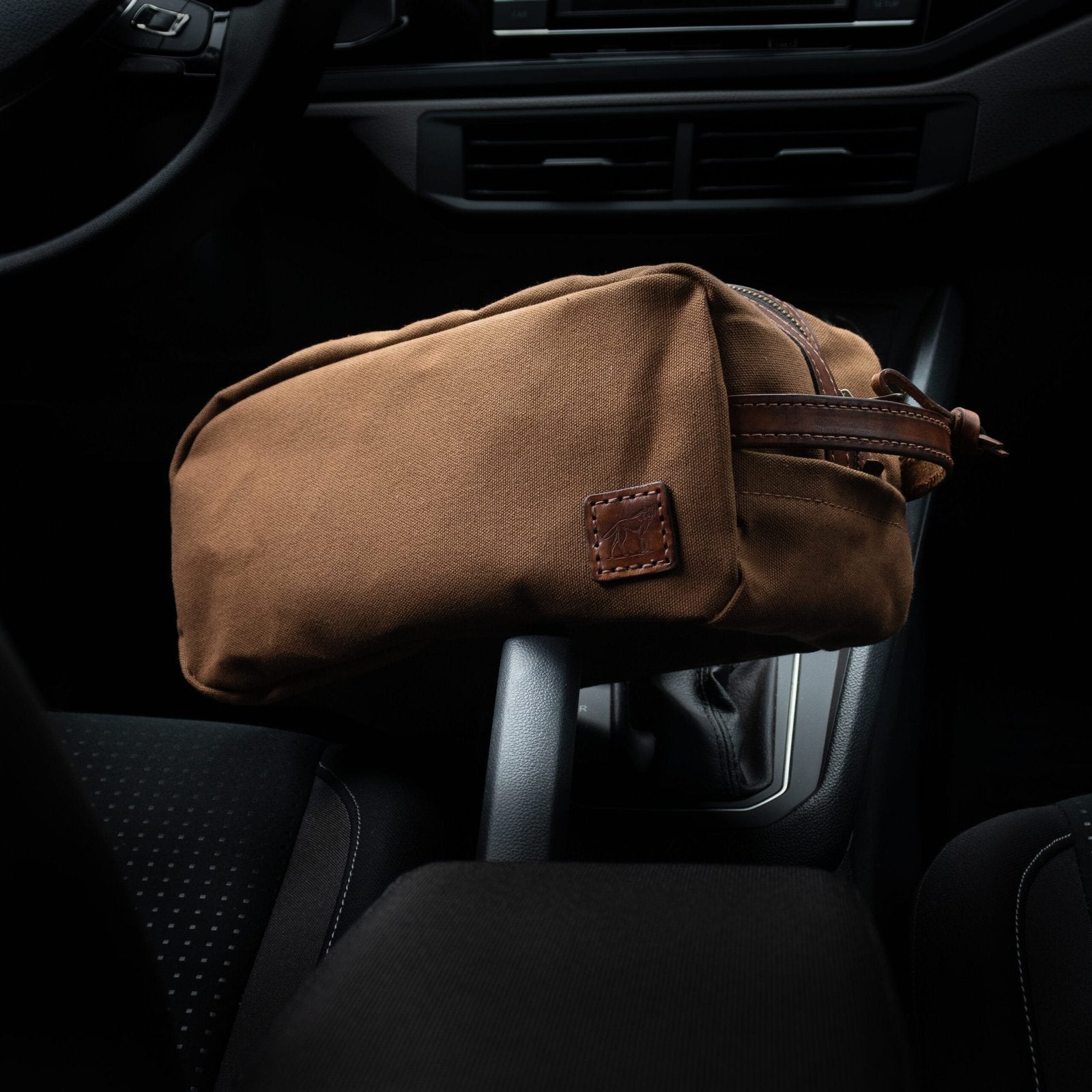 Necessaire Lona Encerada e Couro Marrom em uso, escala comparada à mão – DANTE Capelli