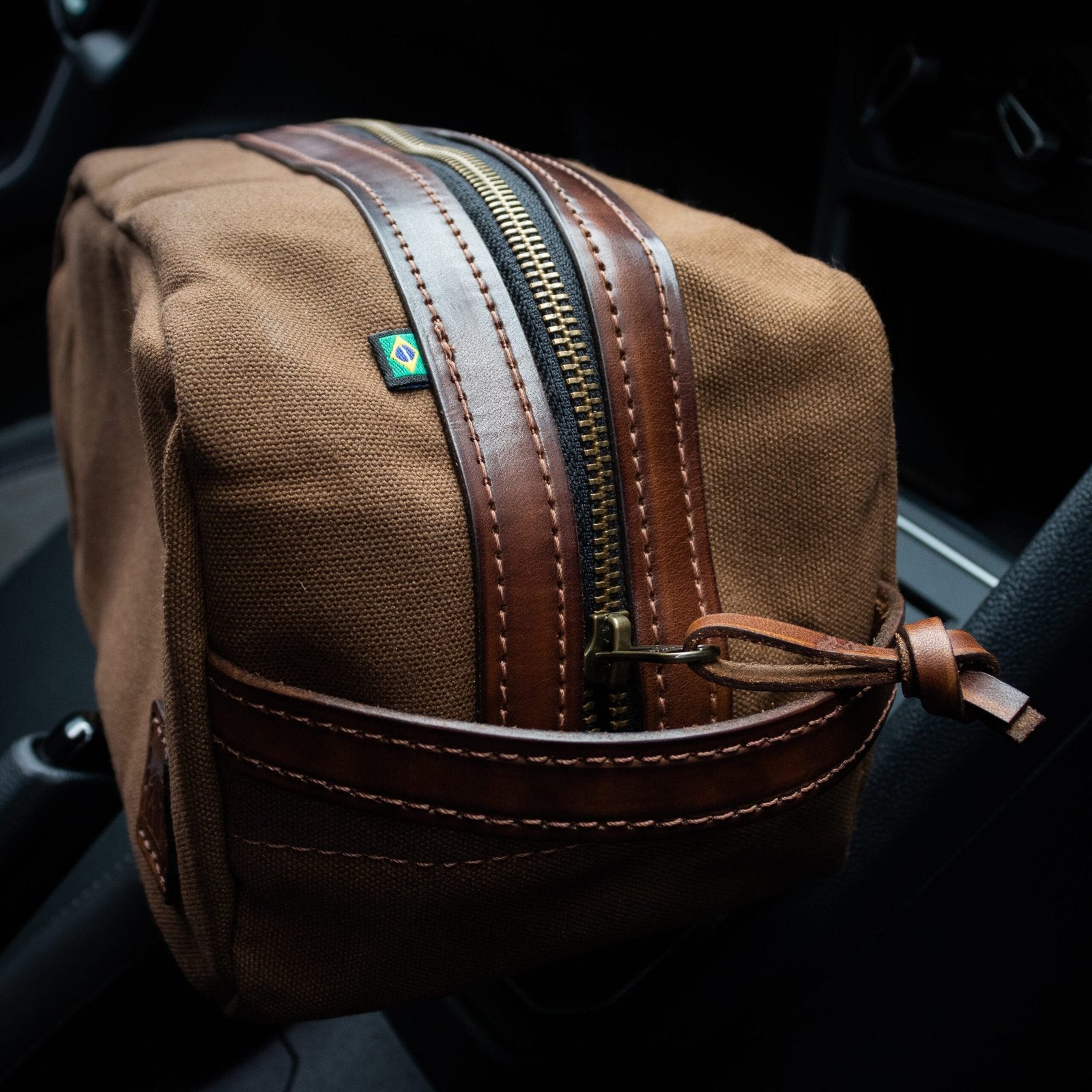 Necessaire Lona Encerada e Couro Marrom, still sobre superfície neutra – DANTE Capelli
